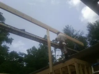 Carpenter setting a ridge beam over a new addition frame — Ice Dam Removal by Roofing Brothers in University