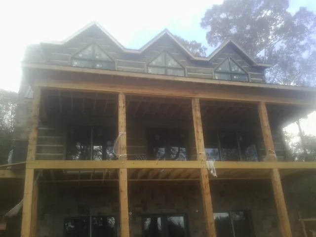Dormers and porch framing on a large log home under construction — Roof Coating work by our crew in University