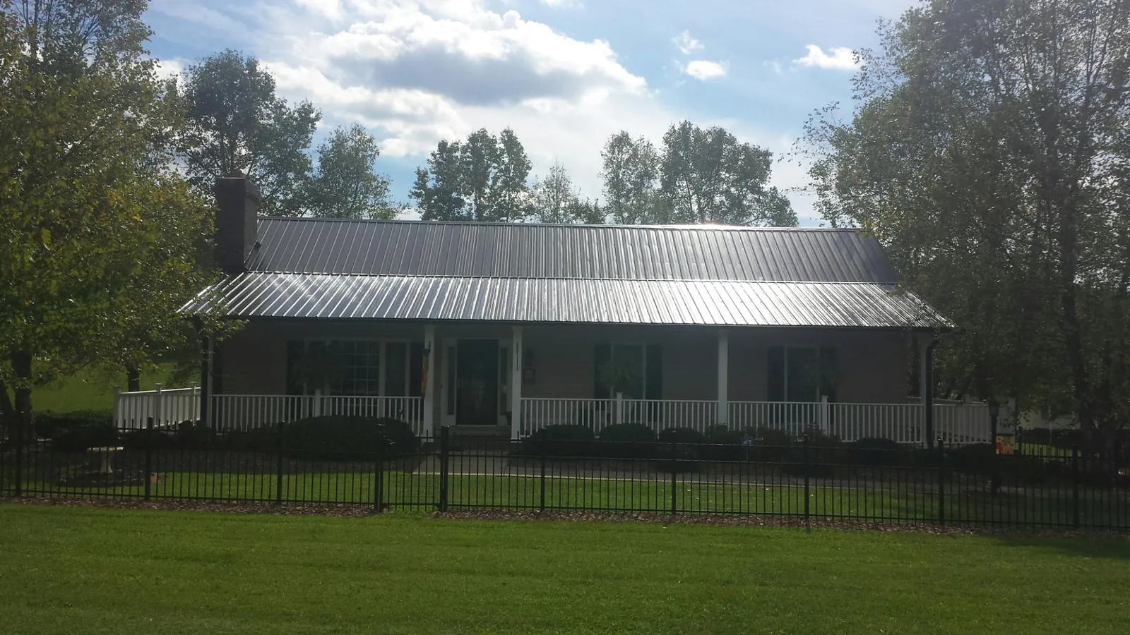 Gray metal roof on a brick ranch with a full width front porch — Gutter Guard Installation work by our crew in University