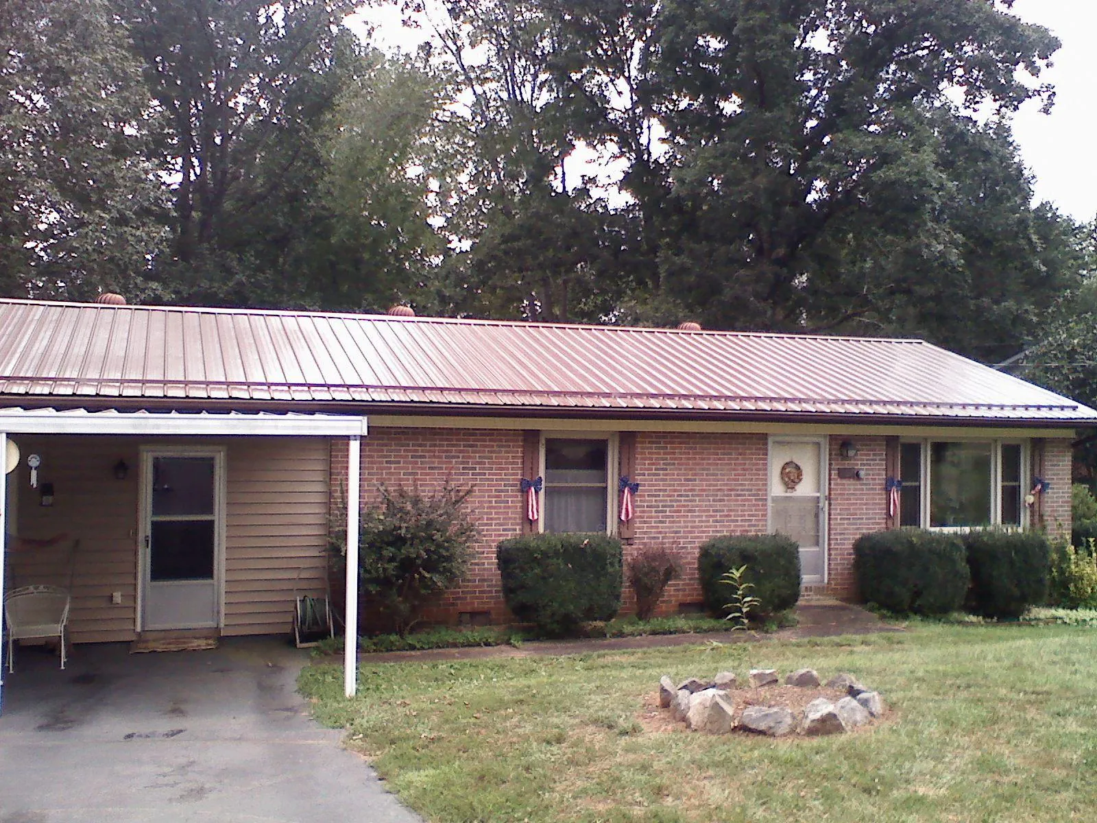 Bronze metal roof and carport on a brick ranch home — Roof Repair work by our crew in University