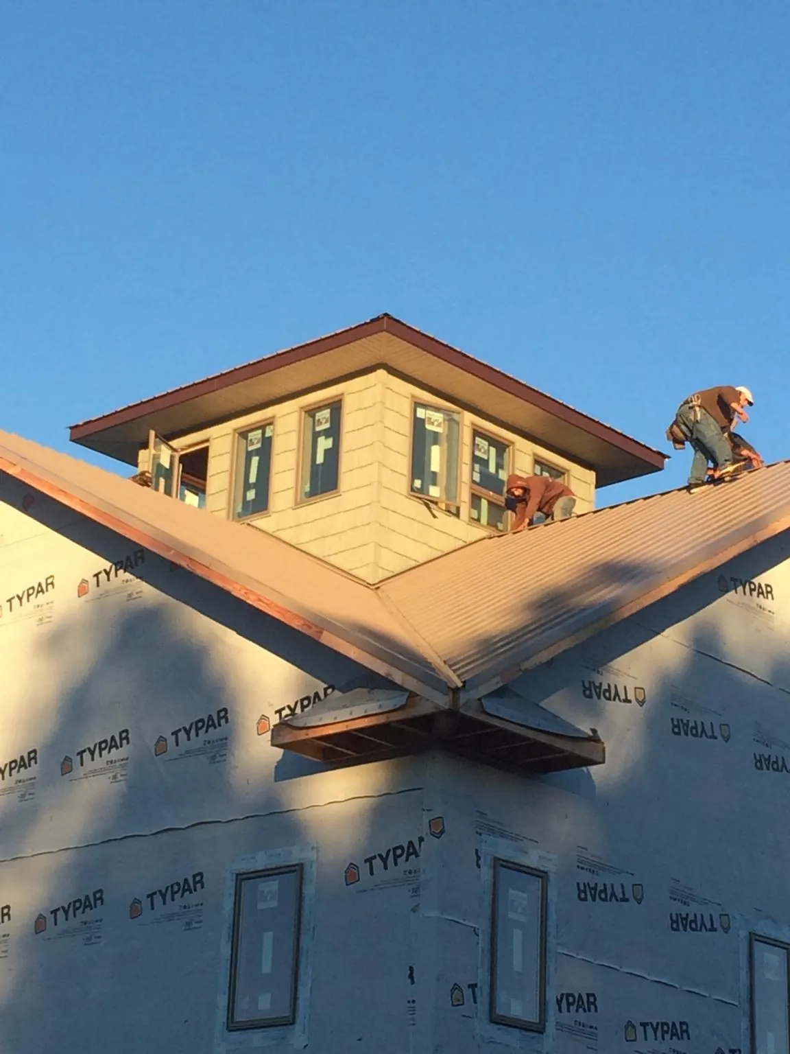 Roofers working around a rooftop cupola on a new metal roof at sunset — Roof Waterproofing in University by Roofing Brothers